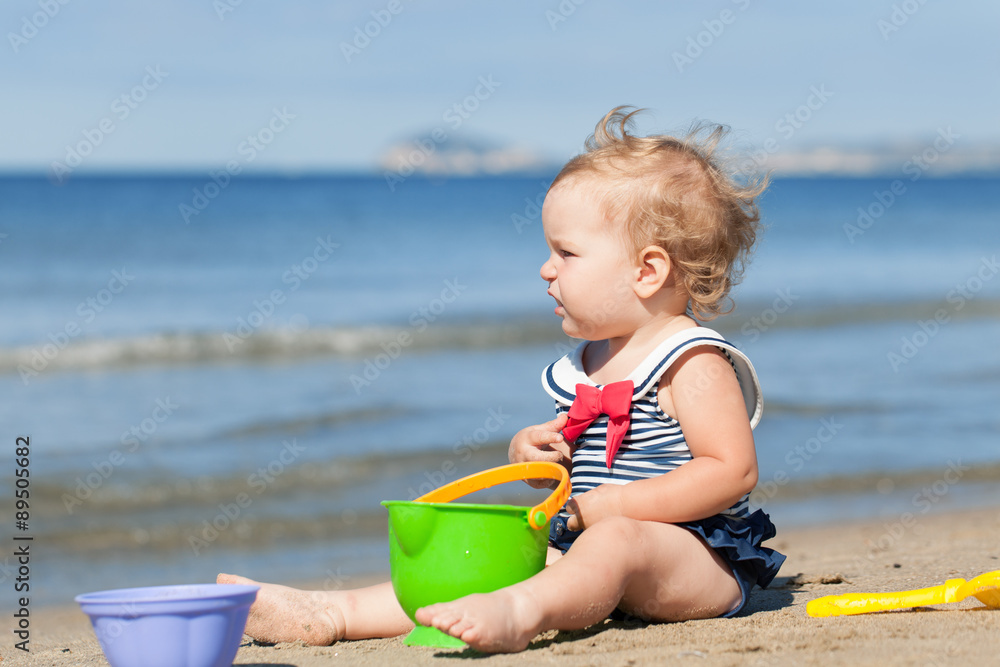 Happy cute girl in swimsuit playing with sand on beach Happy cute girl in swimsuit playing with sand on beach