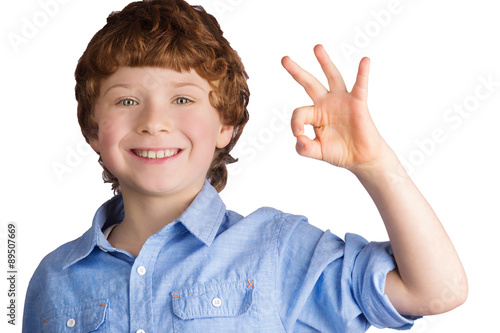 Handsome smiling boy showing OK sign with his hand. Isolated on photo