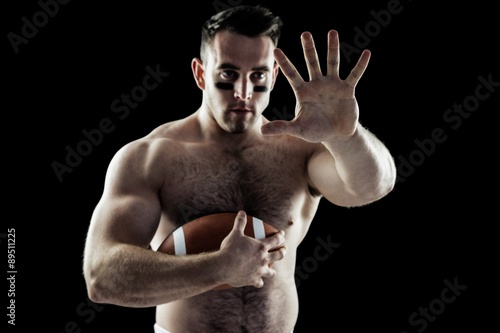 Shirtless American football player with ball