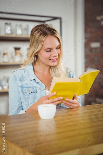 Smiling blonde reading yellow book