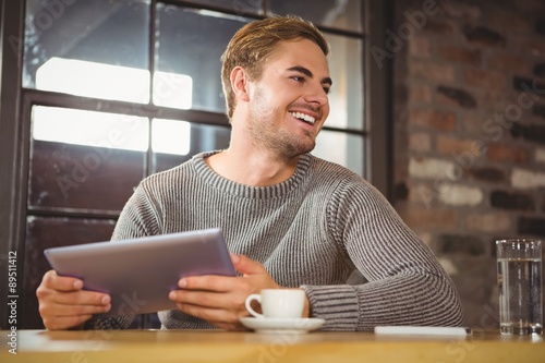 Handsome man smiling and holding tablet computer