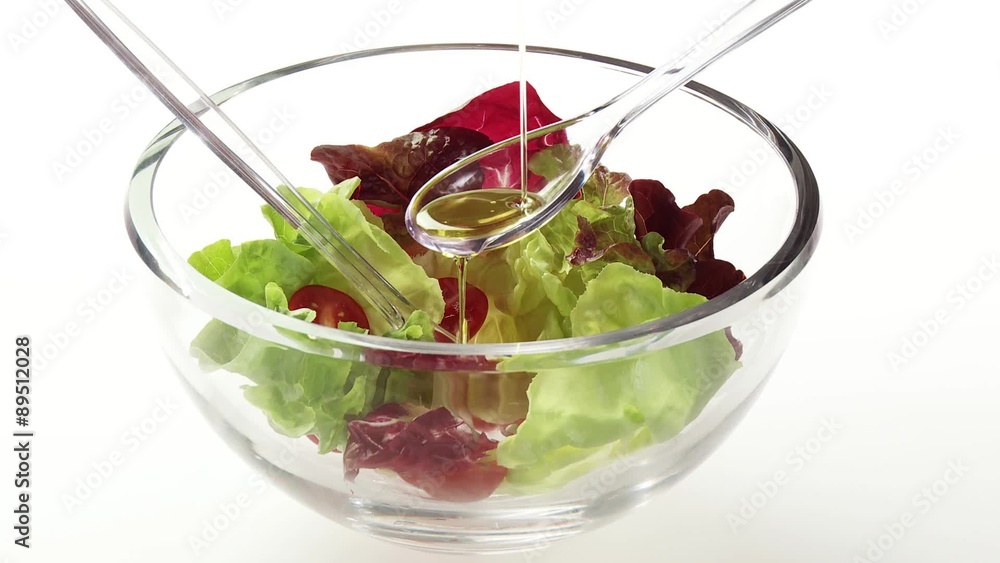 Pouring oil over mixed salad leaves Pouring oil over mixed salad leaves
