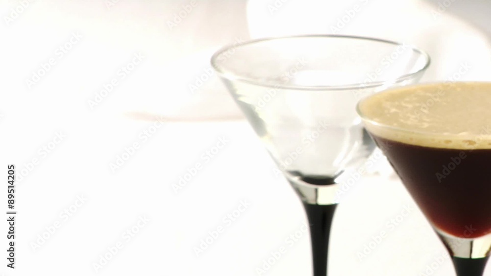 Two cocktail glasses, one empty, one filled with cocktail Two cocktail glasses, one empty, one filled with cocktail