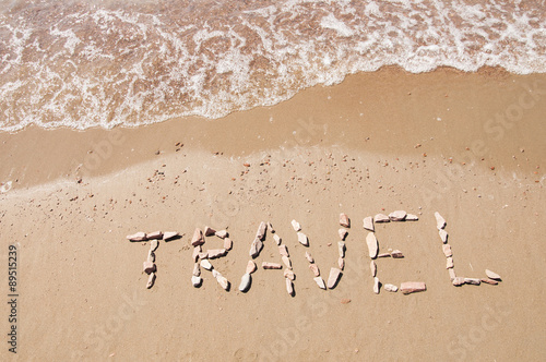 travel written on sandy beach near sea