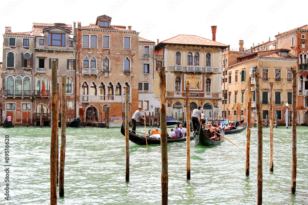 Obraz premium Gondoliers carrying tourists on Grand Canal crossing to the Palazzo Salviati in Venice, Italy