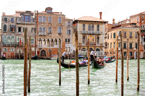 Gondoliers carrying tourists on Grand Canal crossing to the Palazzo Salviati in Venice, Italy  photo