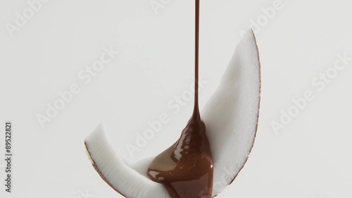 Pouring chocolate sauce over a piece of coconut photo