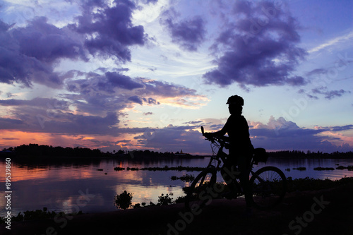 silhouette bike girl at sunset beside the river in countryside o