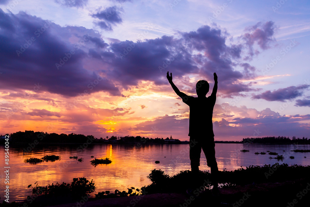 Fototapeta premium Silhouette of a man beside the river at sunset