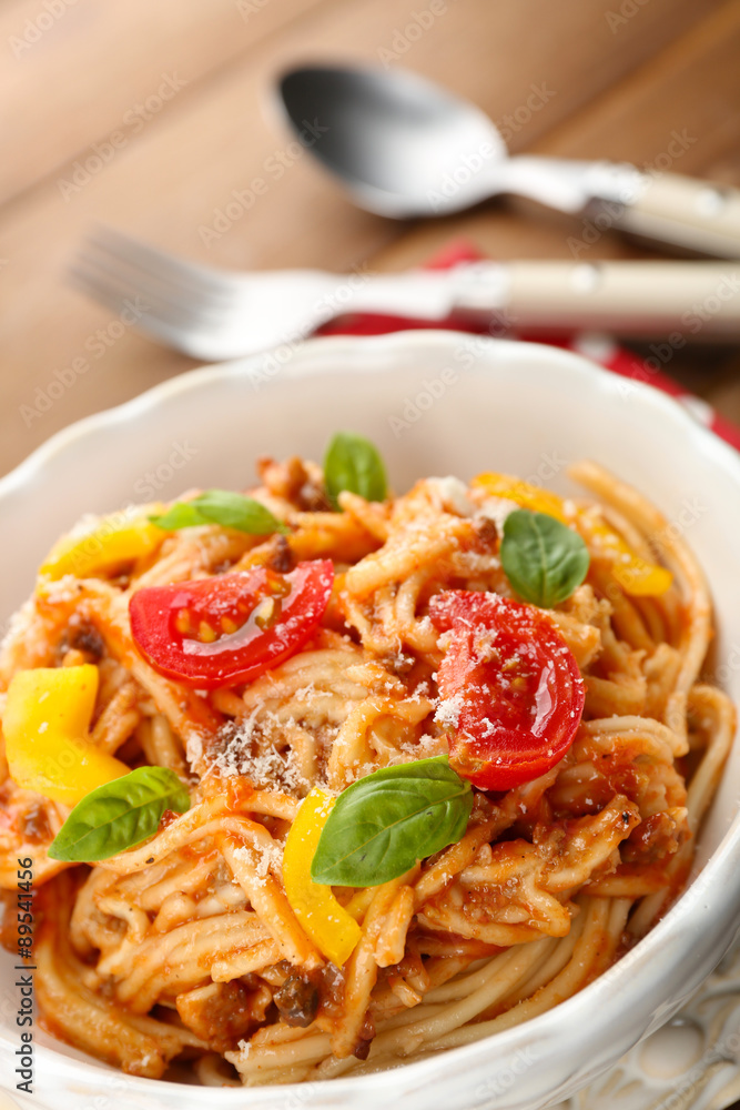 Homemade Spaghetti Bolognese with parmesan cheese in white bowl, on color wooden background