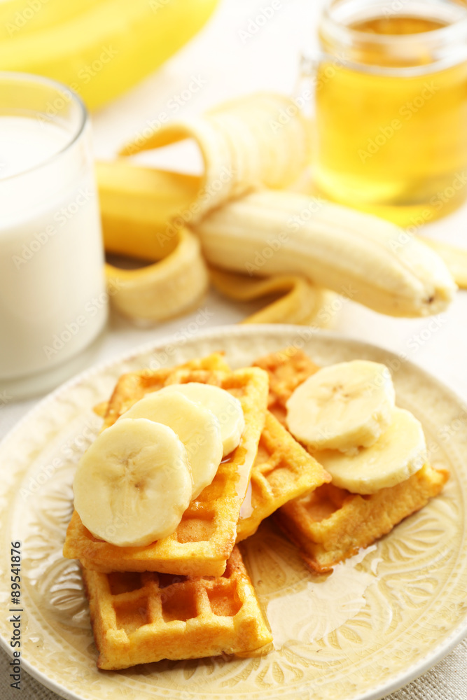 Sweet homemade waffles with sliced banana on plate, on light background Sweet homemade waffles with sliced banana on plate, on light background