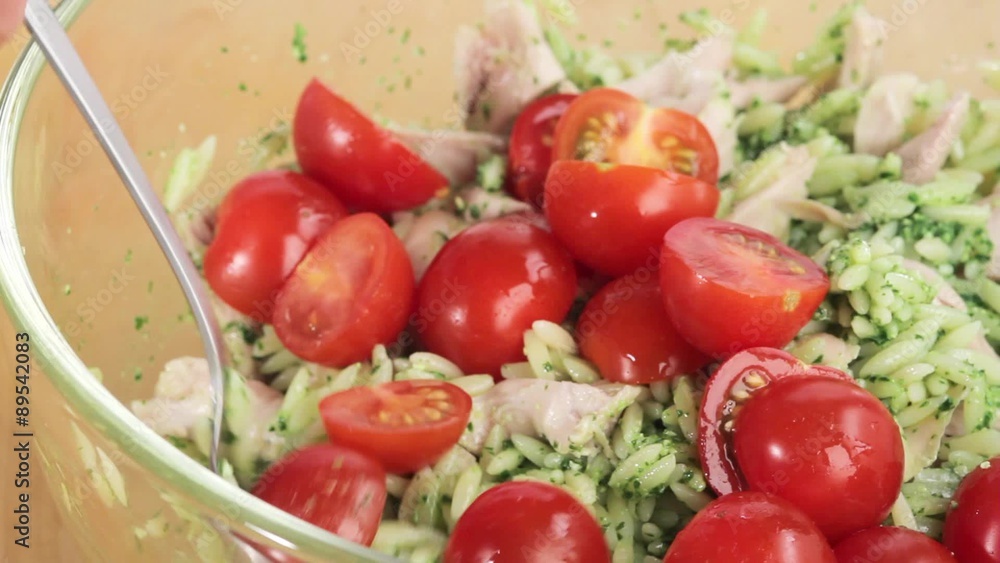 Cherry tomatoes being added to chicken and orzo pasta salad Cherry tomatoes being added to chicken and orzo pasta salad