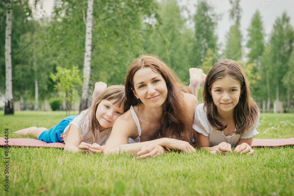 Mother with two young daughters relaxing on the grass Mother with two young daughters relaxing on the grass