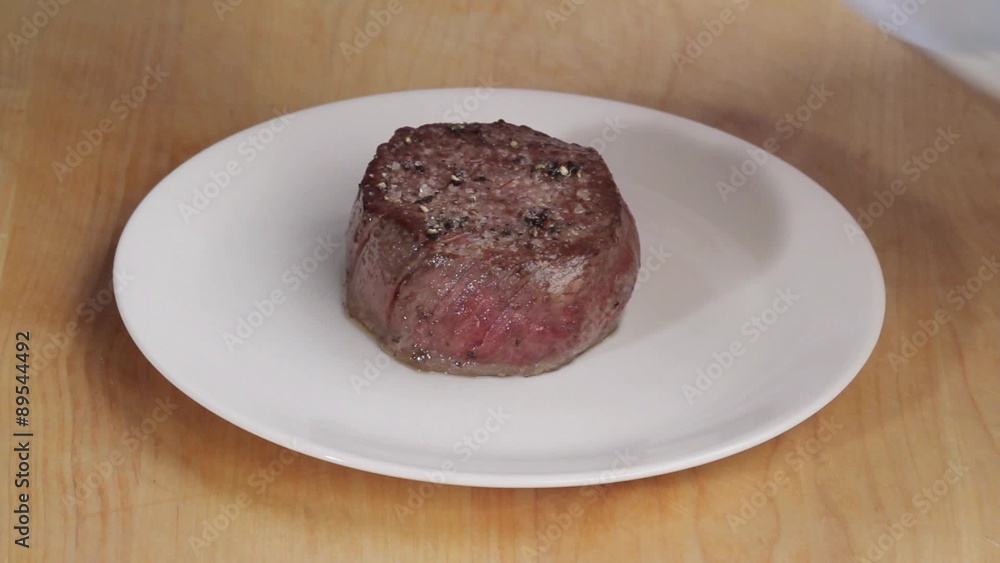 A fried fillet steak being covered with tin foil A fried fillet steak being covered with tin foil