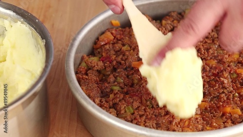 Cottage pie being made: mashed potatoes being placed on top of minced meat