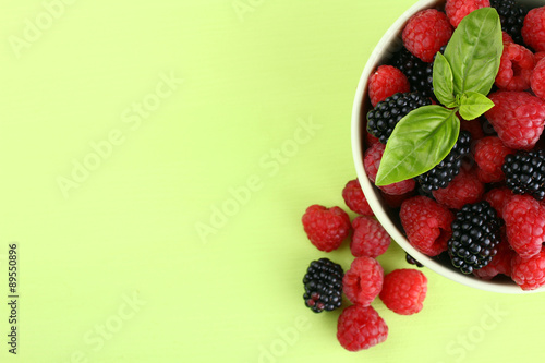 raspberries and blackberries in a bowl of light green background