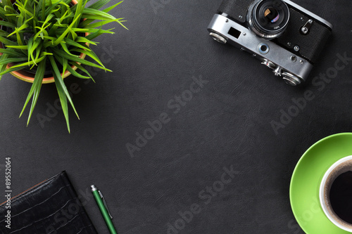 Desk with camera, supplies, coffee cup and flower