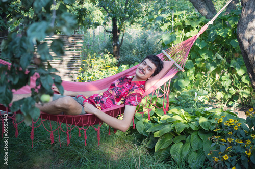 a young man lies  in a red hammock