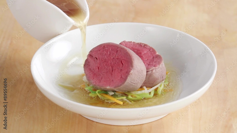 Arranging poached fillet steak with julienne vegetables and broth Arranging poached fillet steak with julienne vegetables and broth