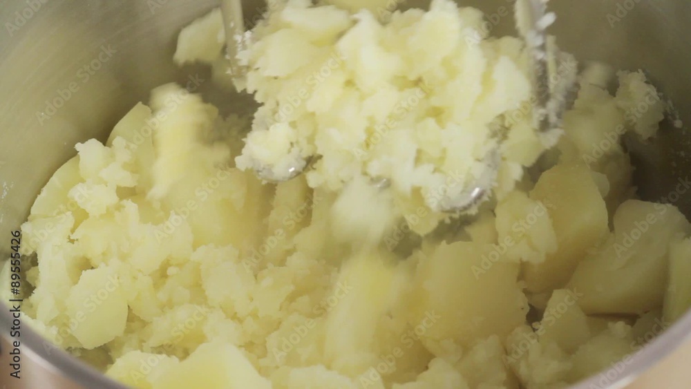 Crushing boiled potatoes with a potato masher Crushing boiled potatoes with a potato masher