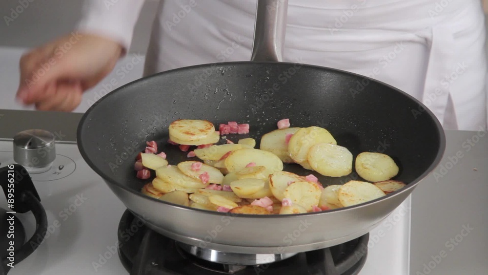 Tossing sauté potatoes with lardons in a frying pan Tossing sauté potatoes with lardons in a frying pan