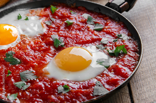 Foto fried eggs in tomato sauce in the pan