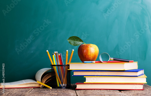 Back to school supplies. Books and blackboard on wooden backgrou