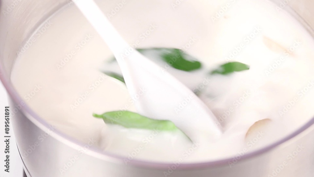 Coconut milk soup with ginger, kaffir lime leaves and lemon grass being simmered Coconut milk soup with ginger, kaffir lime leaves and lemon grass being simmered