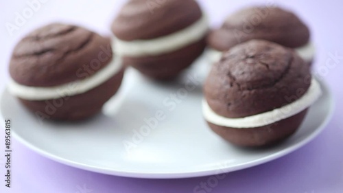 A hand taking a chocolate whoopie pie from a plate