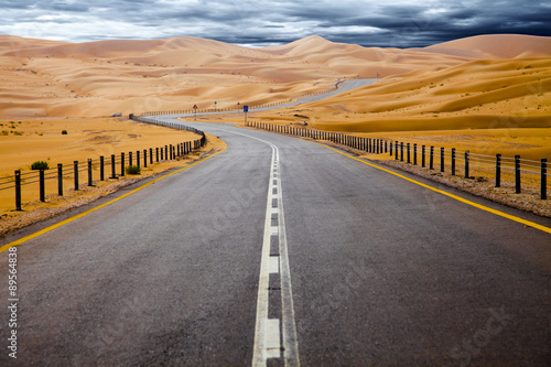 Winding black asphalt road through the sand dunes of Liwa oasis, United Arab Emirates