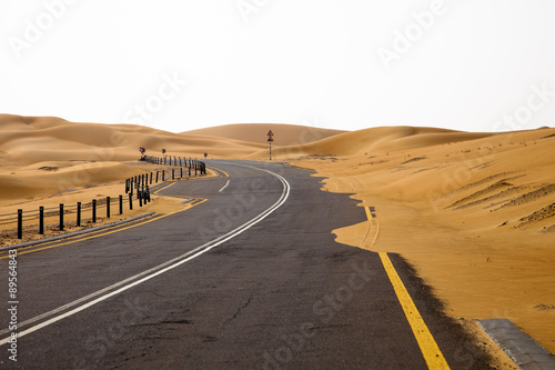 Winding black asphalt road through the sand dunes of Liwa oasis, United Arab Emirates photo