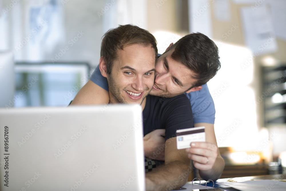 Happy gay couple with laptop shopping online Happy gay couple with laptop shopping online