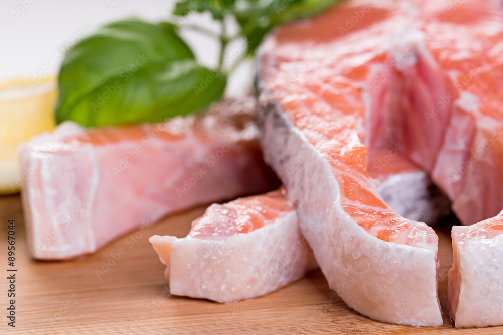 Close up on raw steak of salmon with herbs on wooden cutting board. Close up on raw steak of salmon with herbs on wooden cutting board.
