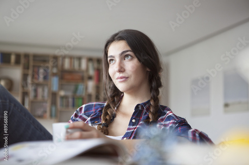 Portrait of young woman with coffee cup relaxing at home photo