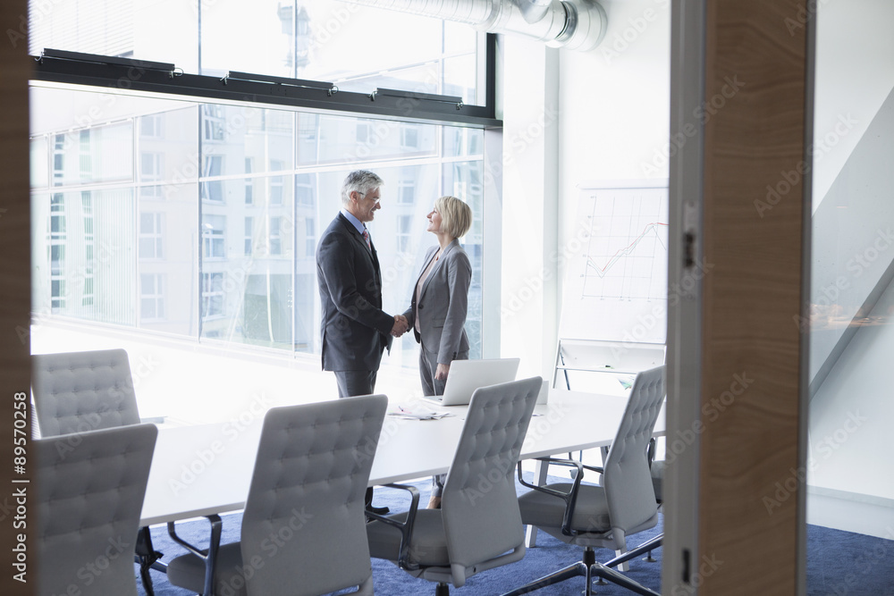 Businessman and businesswoman shaking hands in conference room Businessman and businesswoman shaking hands in conference room