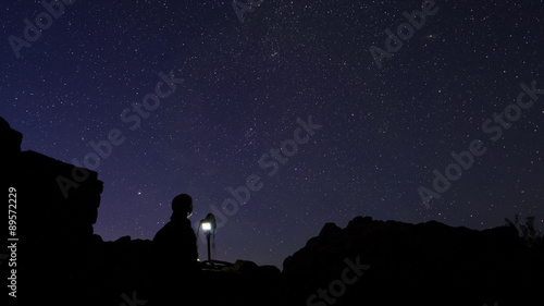 Astrophotographer standing behind his camera insside an old medieval ruin