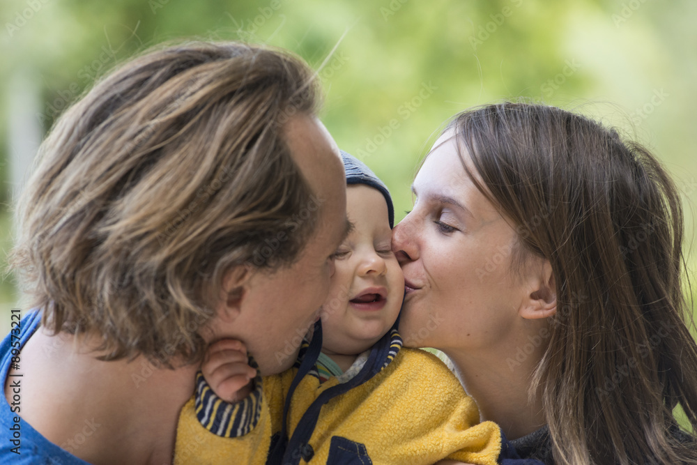 Father and mother kissing their little son Father and mother kissing their little son