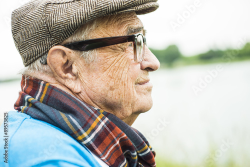 Profile of senior man wearing glasses and cap photo