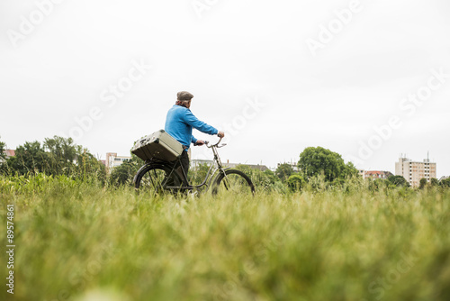 Senior man transporting suitcase on his bicycle