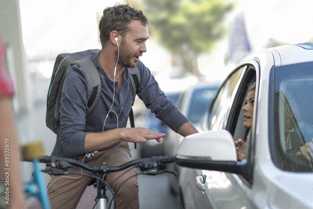 Man on bicycle talking to woman in car Man on bicycle talking to woman in car