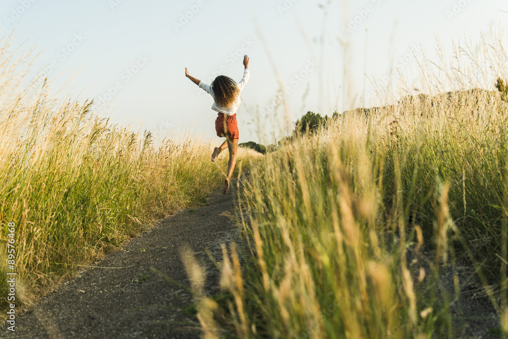 Enthusiastic young woman jumping on path in field Enthusiastic young woman jumping on path in field