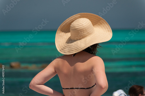 Girl at the beach wearing a straw hat looking out at the Atlanti