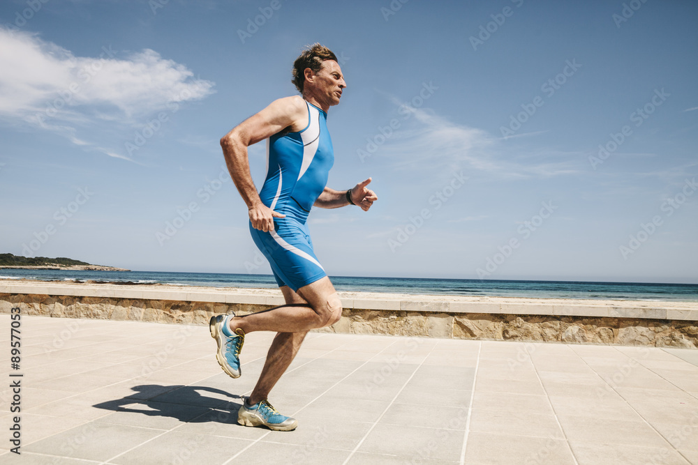 Spain, Mallorca, Sa Coma, triathlete running along beach promenade Spain, Mallorca, Sa Coma, triathlete running along beach promenade