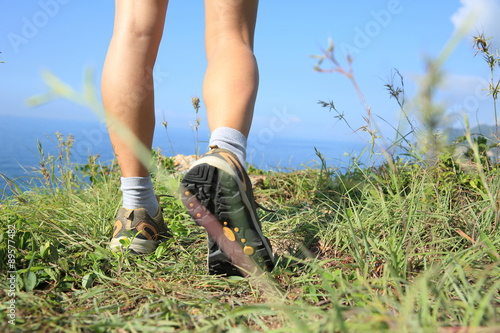 woman hiker legs hiking on seaside mountain grass