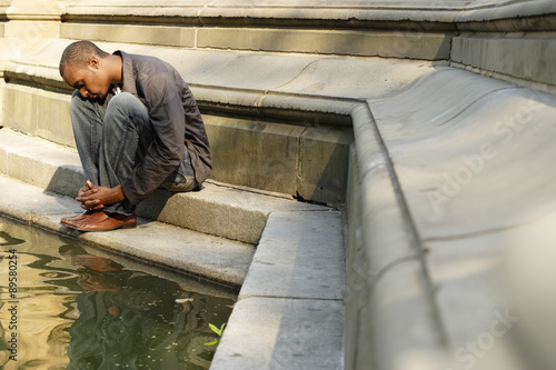 Man sitting on stonework at edge of water. photo