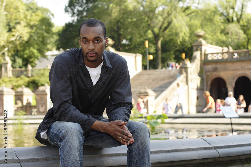 Fototapeta premium Man with clasped hands sitting on edge of fountain.