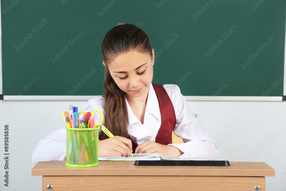 Beautiful little schoolgirl in classroom near blackboard Beautiful little schoolgirl in classroom near blackboard