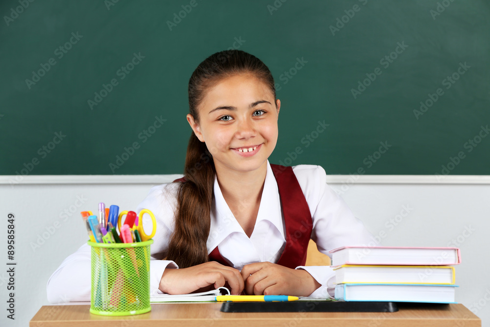 Beautiful little schoolgirl in classroom near blackboard Beautiful little schoolgirl in classroom near blackboard