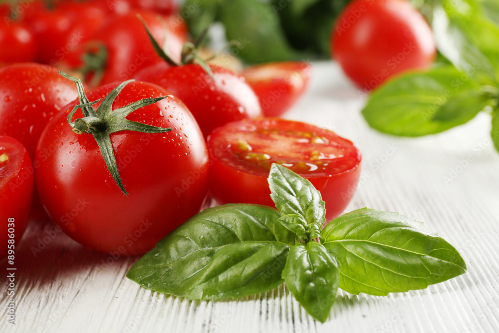 Cherry tomatoes with basil on wooden table close up Cherry tomatoes with basil on wooden table close up