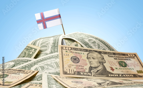 Flag of Faroe Islands sticking in a pile of american dollars.(se